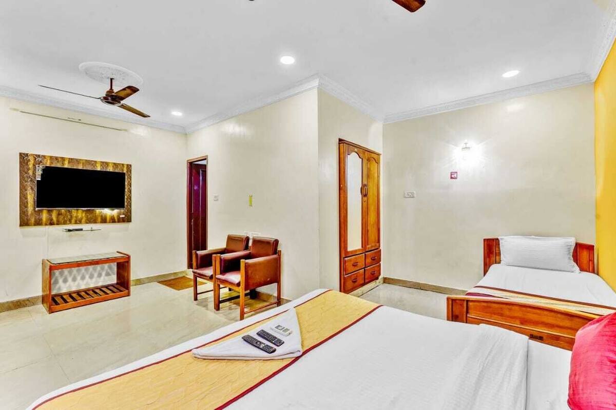 A hotel room with two beds, a TV, a ceiling fan, and a wooden chair.