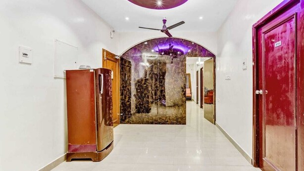 A hallway with a ceiling fan, a marble wall, and a red door. - Hommetree T Nagar (Chennai)