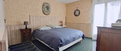A bedroom with a bed, a nightstand, a lamp, a dresser, and a window.