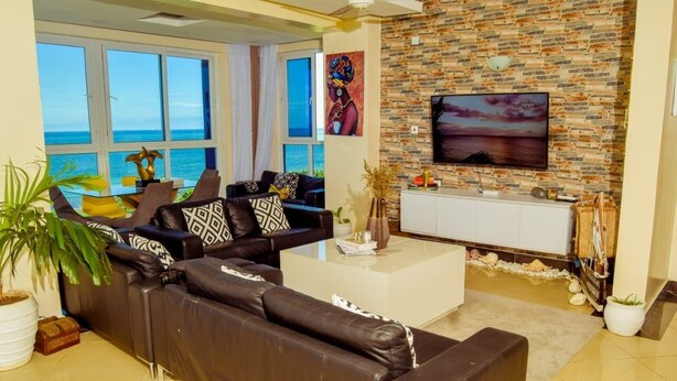 A living room with a leather sofa, a coffee table, and a TV on a brick wall. - Emirates reef (Mombasa)