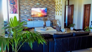 A living room with a stone wall, a flat-screen TV, a sofa, and a coffee table. - Emirates reef (Mombasa)