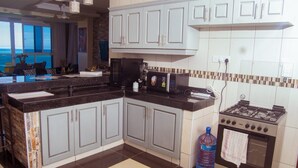 A kitchen with a large island, white cabinets, a gas stove, and a water dispenser. - Emirates reef (Mombasa)
