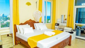 A hotel room with a large bed, a bedside table, a mirror, and a view of the city. - Emirates reef (Mombasa)