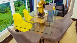 A modern dining area with a glass table, yellow chairs, and a brown sofa. - Emirates reef (Mombasa)