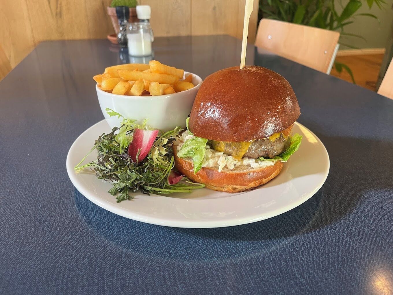 Una hamburguesa con pan, lechuga y una porción de papas fritas en un plato.
