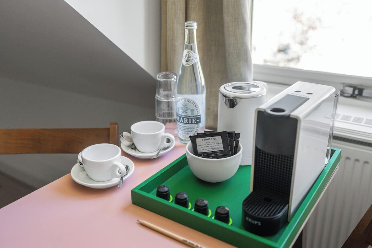 Bandeja de desayuno con una botella de agua Marie-Naturelle, una cafetera, un juego de té y una caja de bolsitas de té.