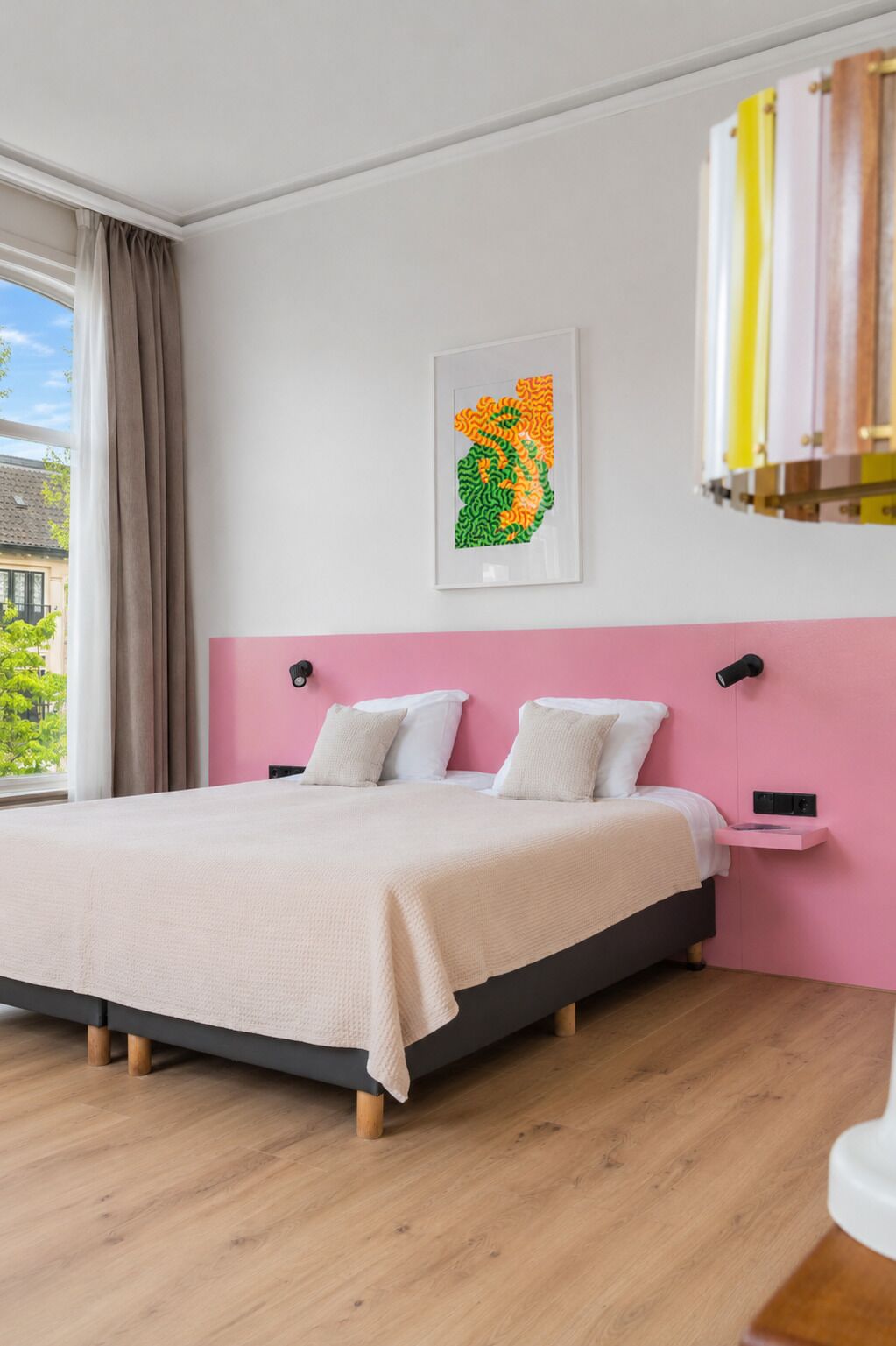 Ein modernes Schlafzimmer mit Bett, einer Wand in Rosa, einem Fenster mit Vorhängen und einem gerahmten Kunstwerk.