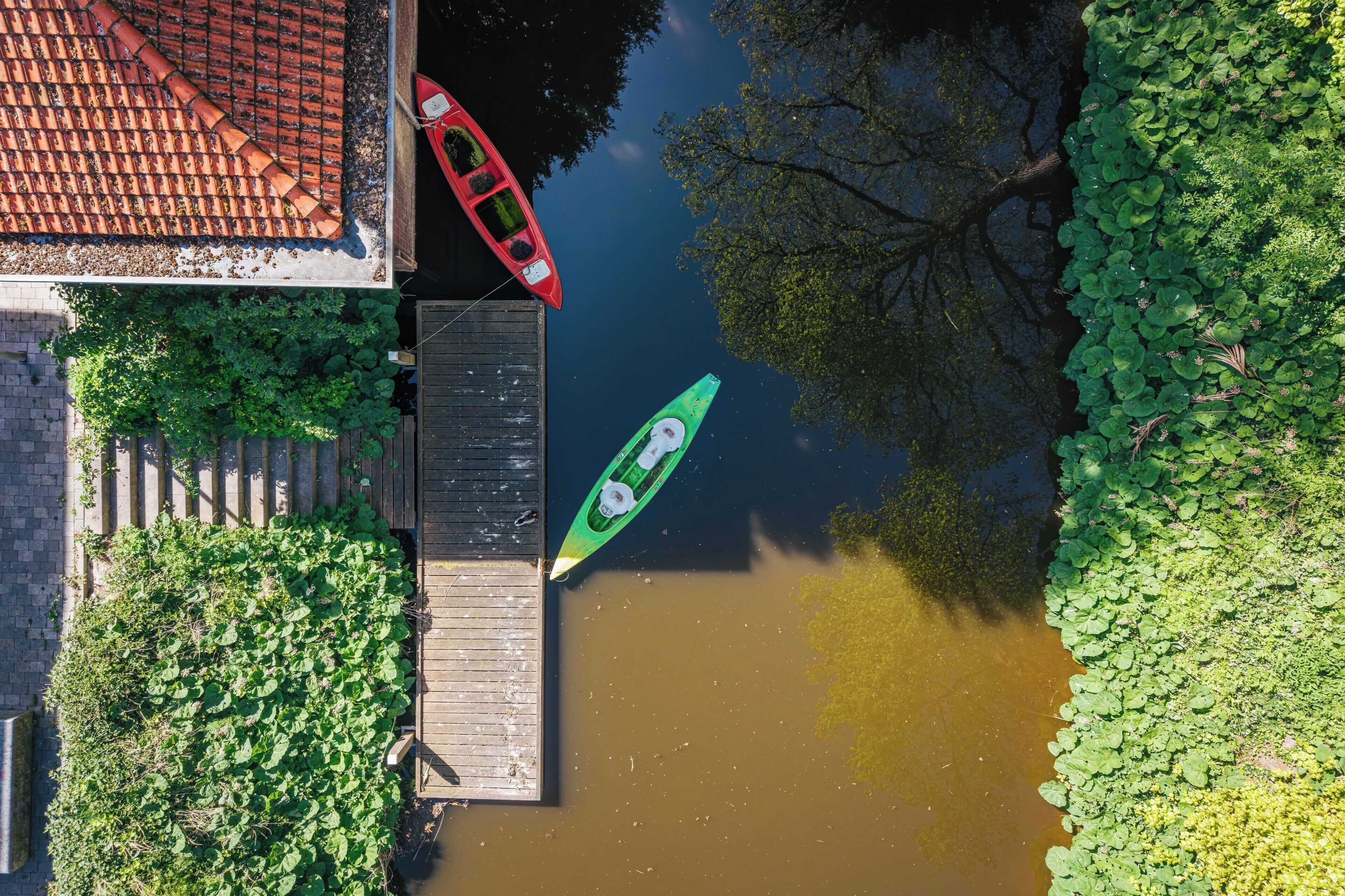 Ein Fluss mit zwei Kajaks, einer Holzsteganlage und einem Gebäude mit einem Ziegeldach.