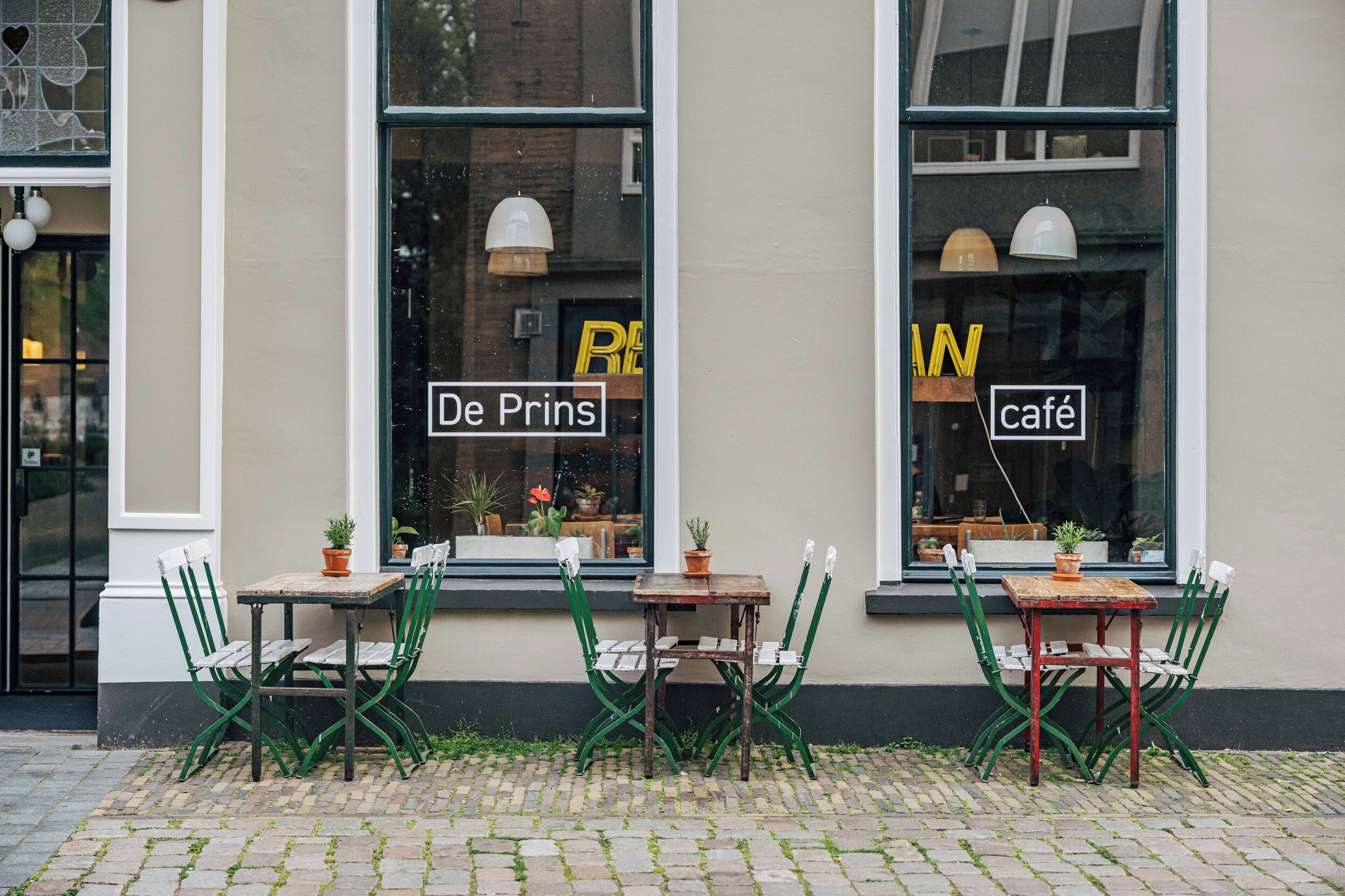 A café with outdoor seating, two tables, and chairs.
