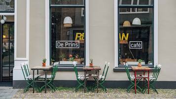 A café with outdoor seating, two tables, and chairs.