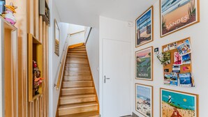 A staircase leading to a room with a white door, wooden paneling, and various travel-themed posters on the walls. - Double Room 'Coquelicot' with Saltwater Pool, Shared Terrace & Garden (Parentis-en-Born)