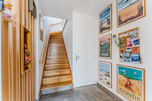 A staircase leading to a room with a white door, wooden paneling, and various travel-themed posters on the walls. - Double Room 'Coquelicot' with Saltwater Pool, Shared Terrace & Garden (Parentis-en-Born)