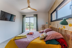 A bedroom with a bed, a ceiling fan, a window, and a TV. - Double Room 'Coquelicot' with Saltwater Pool, Shared Terrace & Garden (Parentis-en-Born)