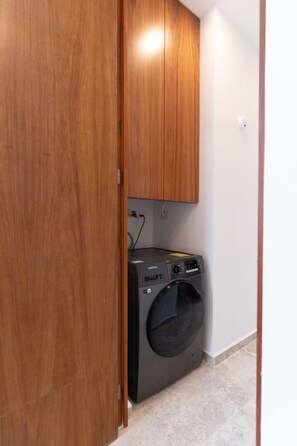 A laundry room with a washing machine and cabinets. - Secreto de Montebello by Kanaa | 1 bd 1.5 bth condo in Northen Merida (Merida)