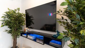 Een flatscreen televisie bevestigd aan een muur, met daaronder een plank met boeken en decoratieve objecten.