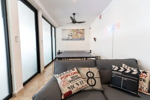 Un salon avec un canapé, une table de ping-pong et un ventilateur de plafond.