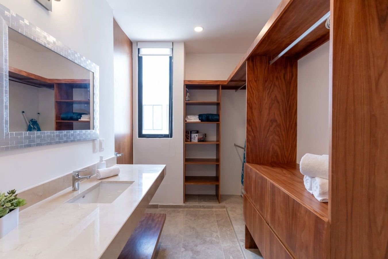 A modern bathroom with a large mirror, a sink, a shower, and a wooden vanity.