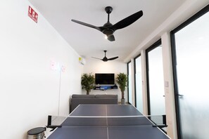 A ping pong table in a room with ceiling fans, a TV, and a plant. - Atardeceres de Montebello by Kanaa | 1 bd 1.5 bth condo in Northen Merida (Merida)