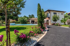 Un immobile residenziale con piscina, vialetto e giardino curato con fiori rosa.