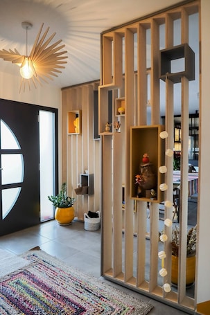 A modern interior with a wooden partition, a hanging light fixture, a potted plant, and a colorful rug.. Bed and Breakfast 'Chambre Double Perroquets' with Shared Terrace, Shared Garden and Wi-Fi