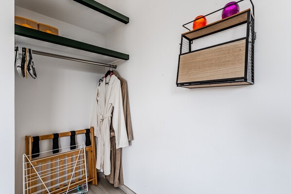 Une pièce avec un étendoir en bois, une robe suspendue et une étagère contenant des récipients.
