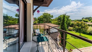 Een balkon met een glazen deur, een stoel en een tafel.