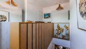 Een modern interieur met een houten scheidingswand, een ingelijst botanisch printje en hanglampen.