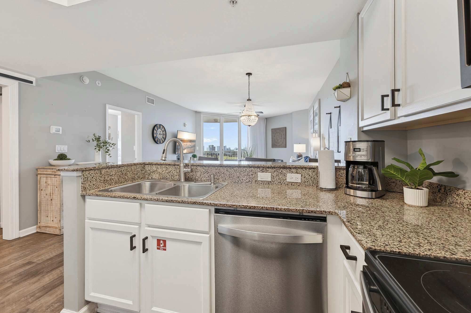 A modern kitchen with granite countertops, stainless steel appliances, and a view to the outside.