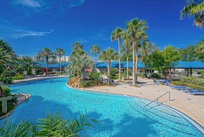 Une piscine avec des chaises longues et des palmiers.