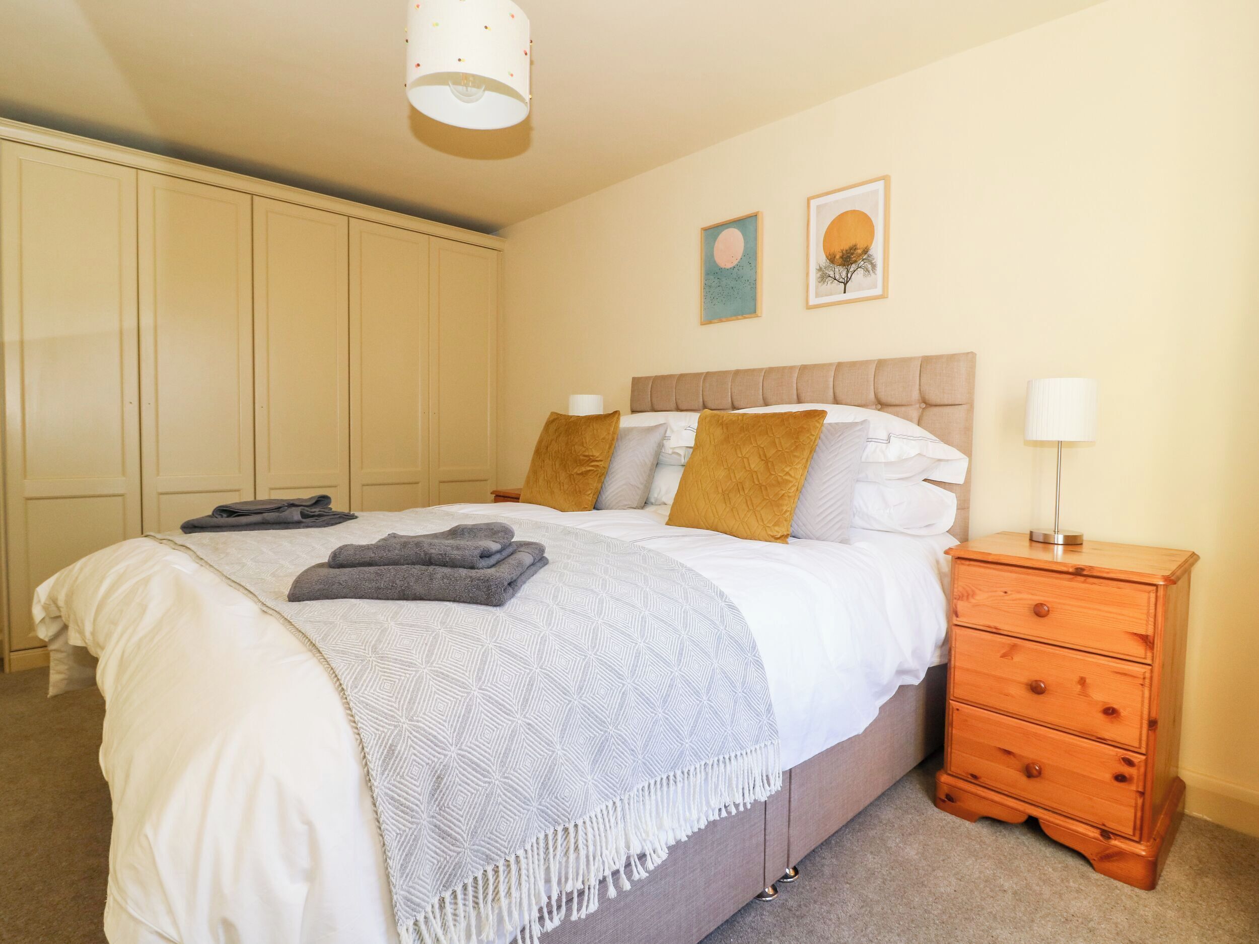 A bedroom with a bed, a nightstand, a wooden dresser, and a wardrobe.