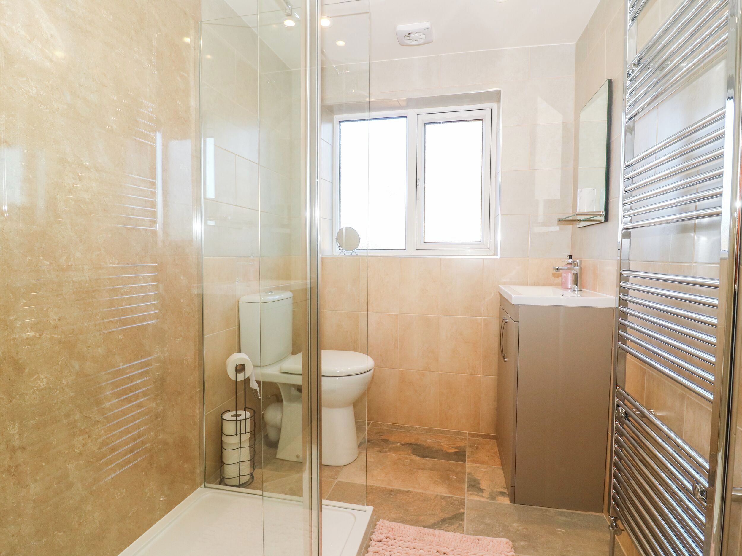 Een badkamer met een douchecabine van glas, een toilet, een wastafel en een spiegel.