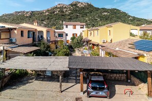 A residential area with houses, a car, and a mountain in the background. - Two-Room Apartment "Le Ginestre" (Vaccileddi)