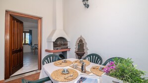 En matplats med ett bord för fyra personer, en pizzaugn och en dekorativ väggdekoration.