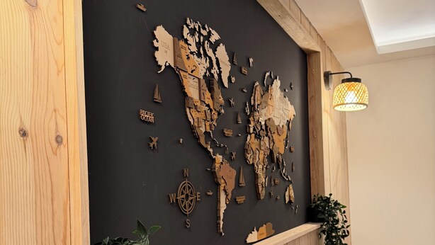 Una parete con una mappa, una bussola, pannelli in legno e una pianta.