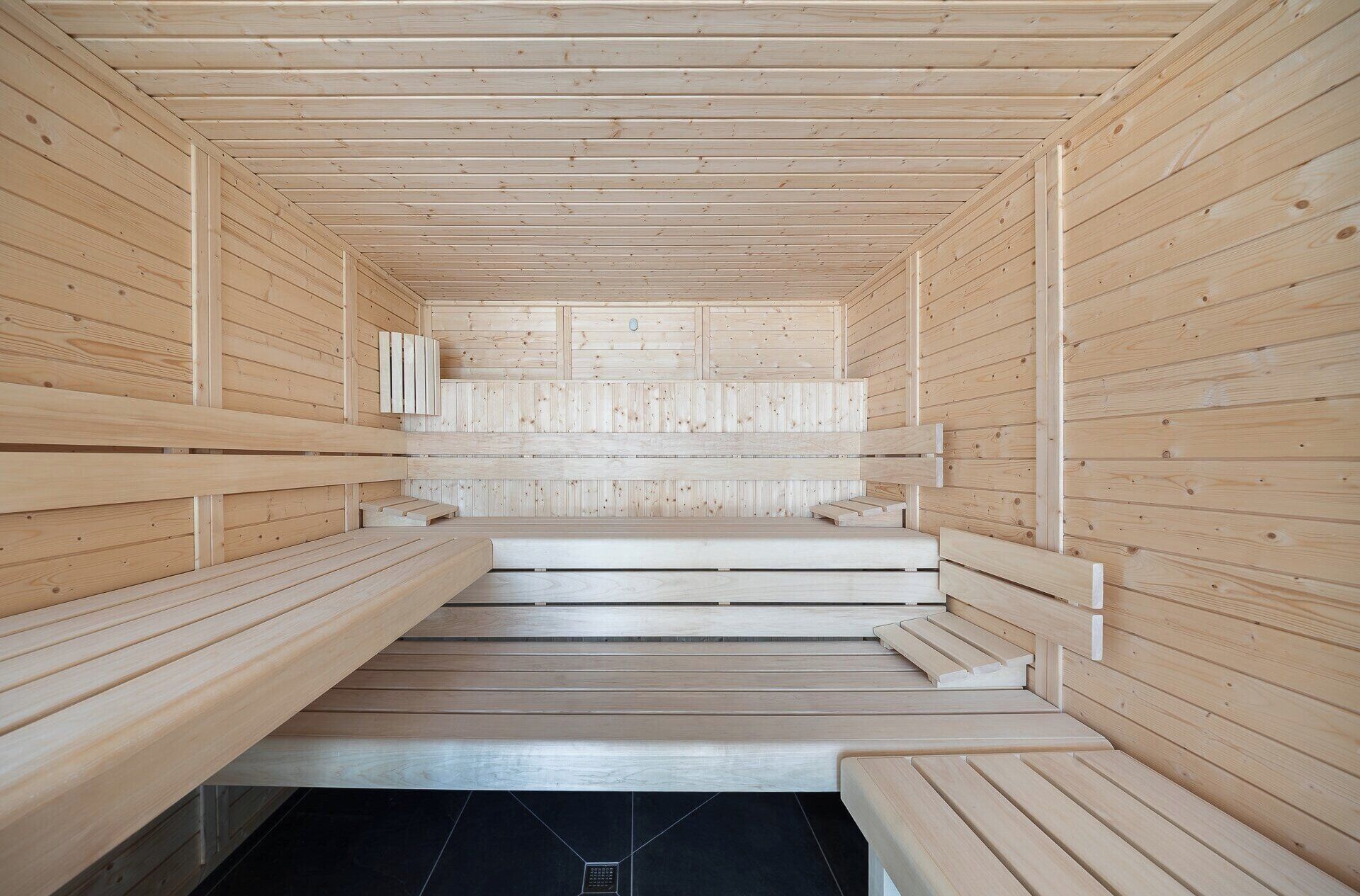 Una sauna con bancos de madera y piso de baldosas.