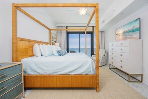 Un letto a baldacchino con vista sull'oceano, un comò bianco e un quadro raffigurante una spiaggia.