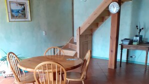 Ein Essbereich mit Holztisch und -stühlen, einer Wanduhr und einer Treppe im Hintergrund.