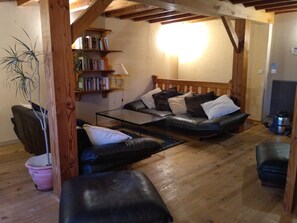 A cozy living room with a leather sofa, a glass coffee table, wooden bookshelves, and a potted plant. - Holiday Home 'La Claire Fontaine' with Wi-Fi (Saint-Just-en-Bas)