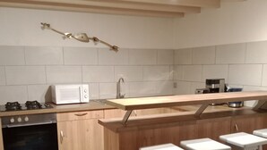 Eine Küche mit Mikrowelle, Herd, Spüle, Holzschränken und einem farbenfrohen Boden.