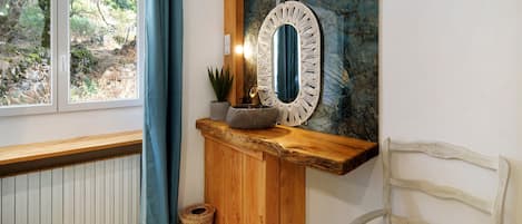 A room with a bench, a wooden counter, a mirror, a potted plant, and a chair.