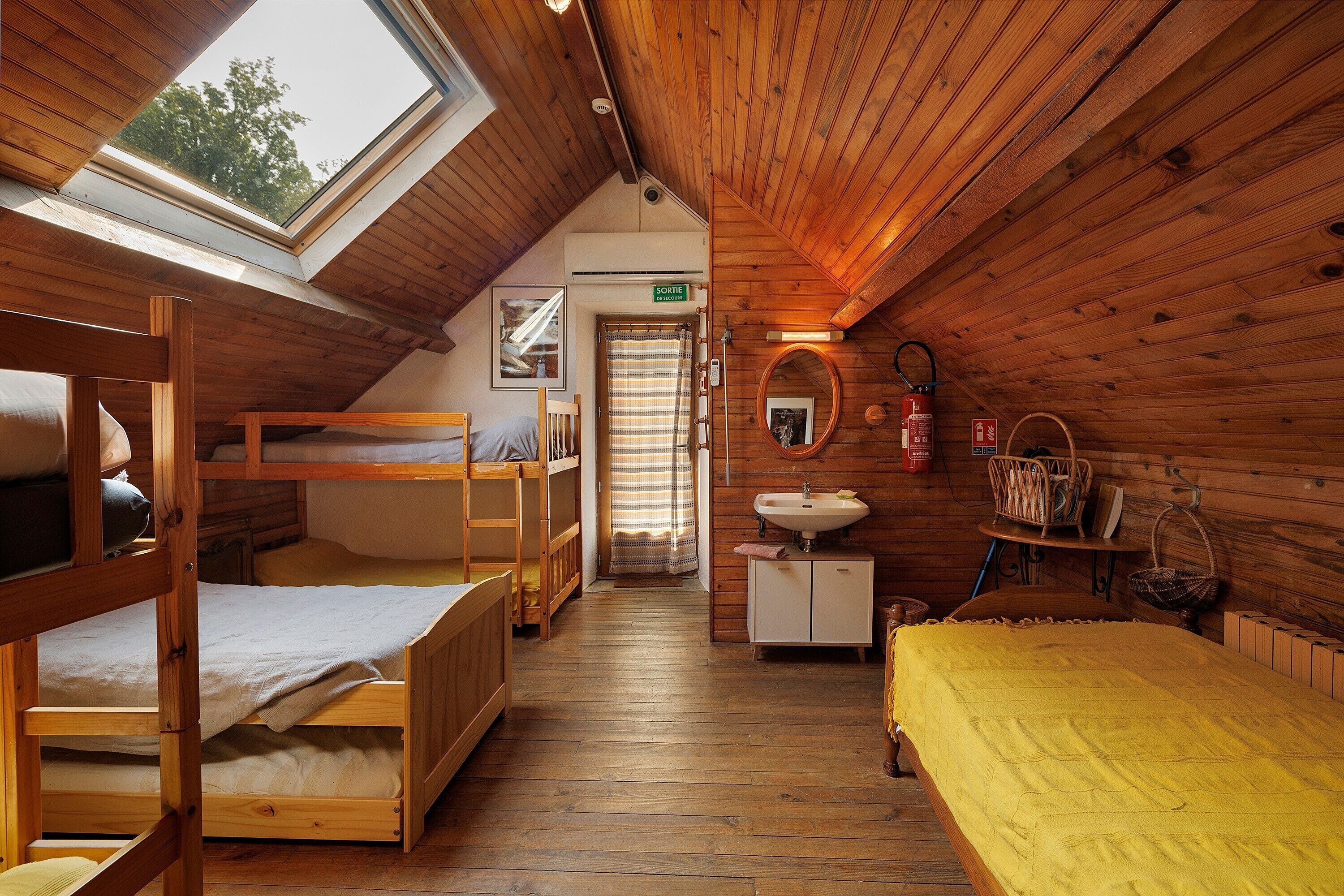 Ein gemütliches Holzhütten-Zimmer mit Etagenbetten, einem kleinen Waschbecken und einem Fenster mit Blick auf Grünflächen.