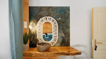 A wooden bench with a stone bowl, a potted plant, and a wall-mounted mirror with a decorative frame.