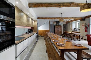Una cocina moderna con una mesa larga y un mantel preparado para una comida.