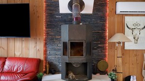 Ein modernes Wohnzimmer mit Steinwand, Kamin, Ledersofa und Flachbildfernseher.