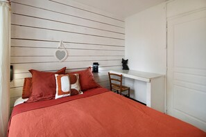 Une chambre à coucher avec un lit, des oreillers, un miroir, un bureau et une chaise.