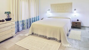 A bedroom with a bed, bedside tables, a dresser, a potted plant, and a wall-mounted air conditioner. - Residence with swimming pool in Santa Margherita di Pula (Santa Margherita di Pula)