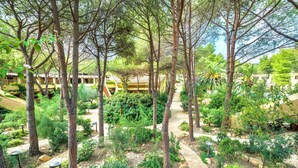 A lush garden with tall trees and a paved walkway. - Residence with swimming pool in Santa Margherita di Pula (Santa Margherita di Pula)