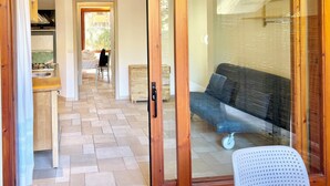 A room with a sliding glass door leading to a balcony, a sofa, and a small table. - Residence with swimming pool in Santa Margherita di Pula (Santa Margherita di Pula)