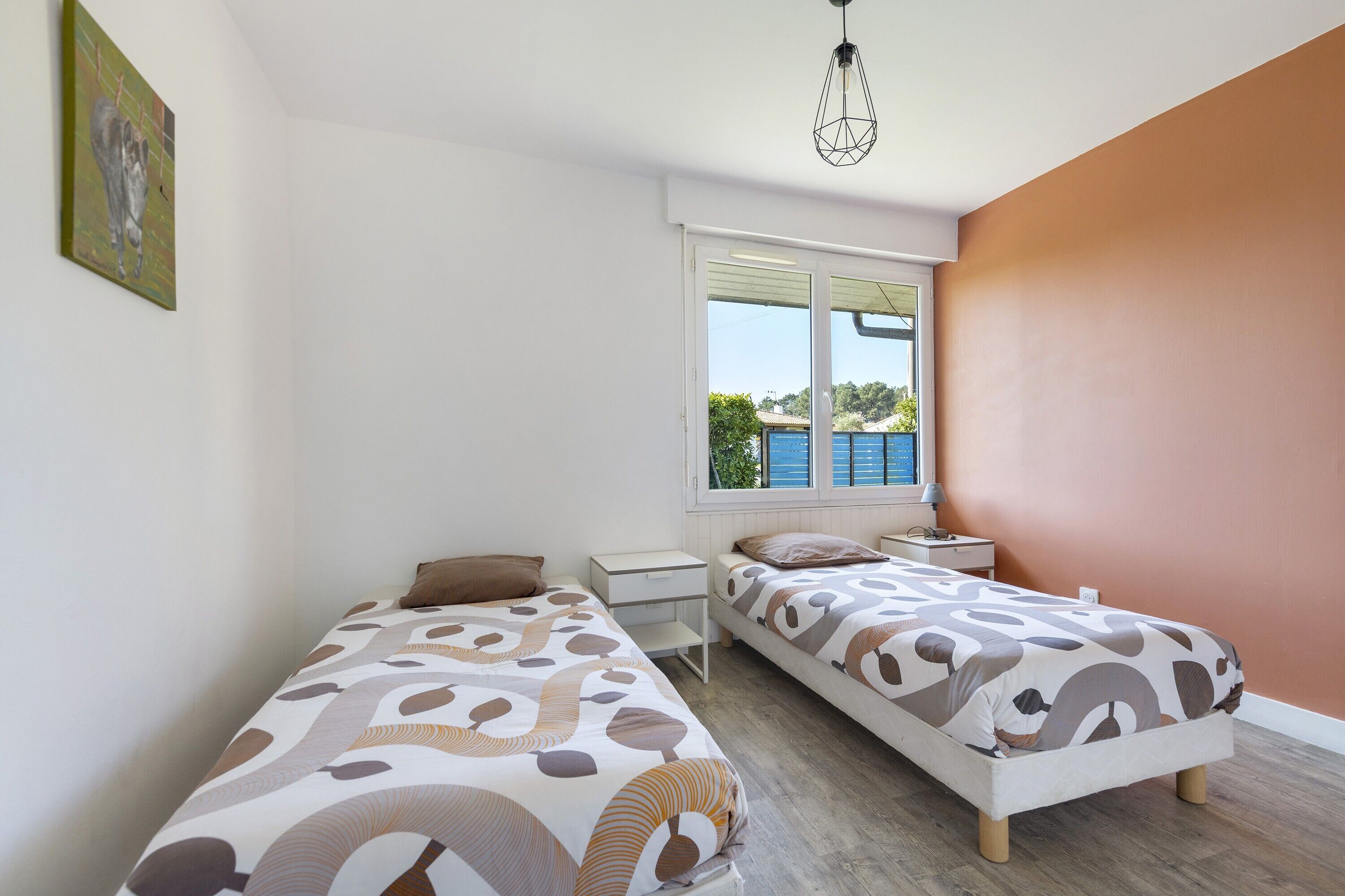Un dormitorio con dos camas, una ventana y un cuadro en la pared.