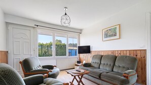 Una sala de estar con sofá, sillones, televisor y ventana con vistas.